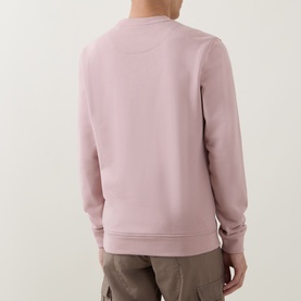 Model wearing Belstaff Logo Badge Sweatshirt in Dusk Pink, rear view, crew neck, ribbed cuffs and hem, paired with khaki trousers.
