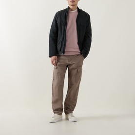 Model wearing Belstaff Logo Badge Sweatshirt in Dusk Pink, styled with black bomber jacket, taupe cargo trousers and white trainers.