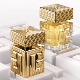 Balmain Parfum duo in gold geometric sculptural bottles with ridged gold caps, displayed on white cube surface
