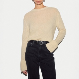 Model wearing Jigsaw cream knit jumper with flared cuffs, styled with black jeans and belt.