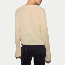 Model wearing Jigsaw cream knit sweater, back view, with flared cuffs, styled with dark jeans