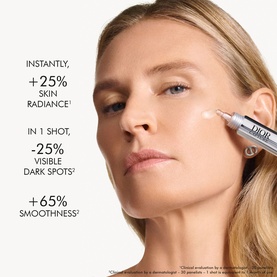 Model with Dior booster treatment pen applied to under-eye area, with skin radiance and dark spot reduction claims visible