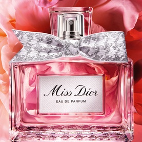 Dior Miss Dior Eau de Parfum in pink glass bottle with silver toile de Jouy bow, styled with pink floral background