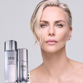 Model with Dior Capture Totale serum and essence lotion bottles displayed beside her against a light grey background