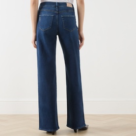 Model wearing Paige Wide Leg Jeans in Admission blue denim, rear view showing five-pocket styling and relaxed wide-leg silhouette.