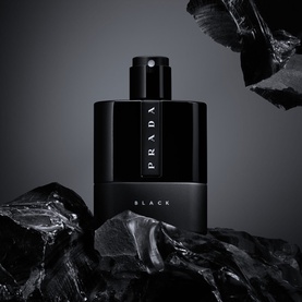 Prada Luna Rossa Black eau de parfum in sleek black bottle with spray cap, styled on dark volcanic rock backdrop
