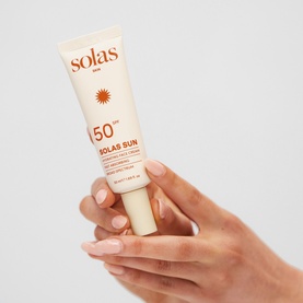Solas Skin Solas Sun SPF 50 face serum tube held in hand, cream-coloured packaging with sun motif branding