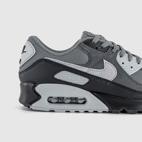 Nike Air Max 90 trainer in grey and black colourway, wolf grey swoosh, visible Air unit, rubber outsole, angled detail shot