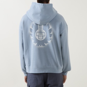 Model wearing Belstaff Mist Blue cotton hoodie, back view showing oversized tonal logo graphic on back, with navy trousers