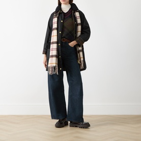 Model wearing Barbour Shadow Classic Tartan knitwear, styled with black wax jacket, checked scarf, wide-leg jeans and chunky loafers.