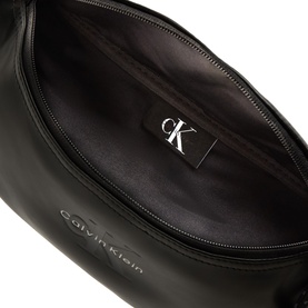 Calvin Klein black bum bag, open view showing black fabric interior lining and silver-tone CK logo label on zip pocket.