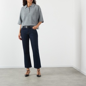 Model wearing FRAME DENIM Rinse slim jeans with a grey knit polo top, brown belt, and black heeled mules.