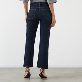 Model wearing FRAME DENIM Slim Jeans in Rinse dark indigo wash, rear view, styled with black strappy heels