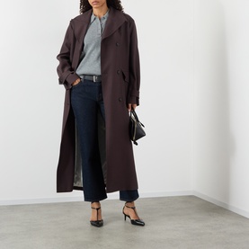 Model wearing FRAME DENIM Rinse slim jeans, styled with a dark burgundy trench coat, grey shirt and black heeled mules