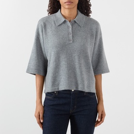 Model wearing FRAME DENIM graphite grey cashmere polo top with short sleeves and button placket, styled with dark navy jeans.