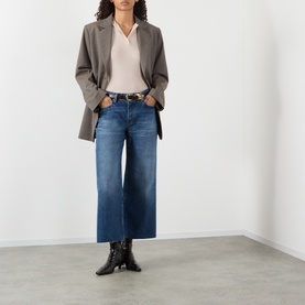 Model wearing FRAME DENIM Wide Leg Jeans in Lucky Raw After blue denim, styled with grey blazer, cream top and black heeled boots.