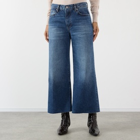 Model wearing FRAME DENIM Wide Leg Jeans in Lucky Raw After blue denim, cropped length, paired with black patent ankle boots and a cream top.