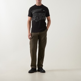 Model wearing Lacoste Crew Neck T in black with oversized crocodile graphic, styled with khaki cargo trousers and black boots.