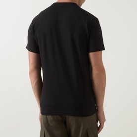 Model wearing Lacoste black crew neck T-shirt, rear view, styled with khaki cargo trousers.