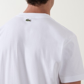 Model wearing Lacoste Crew Neck T-shirt in white, rear view showing iconic green crocodile logo on upper back.