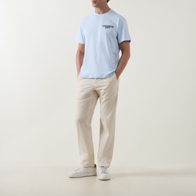 Model wearing Lacoste Crew Neck T in light blue Rill with small chest logo, styled with stone chinos and white trainers