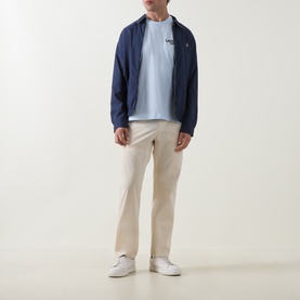 Model wearing Lacoste Crew Neck T in Rill blue, styled with navy zip-up jacket and beige chinos.
