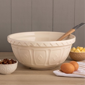 Large cream ceramic mixing bowl with embossed diamond pattern, styled with eggs, dried fruit, and wooden spoon on a wooden surface