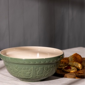 Mason & Cash green ceramic mixing bowl with embossed leaf pattern and cream interior, styled with pastries on linen cloth