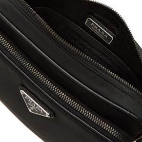 Prada black nylon belt bag open view showing interior compartments, silver triangle logo plaque and zip pockets