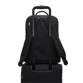 Black backpack with luggage pass-through sleeve, shown mounted on a black rolling suitcase, padded shoulder straps visible at rear