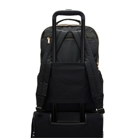 Black backpack with gold-tone zips shown mounted on luggage trolley handle via back pass-through sleeve