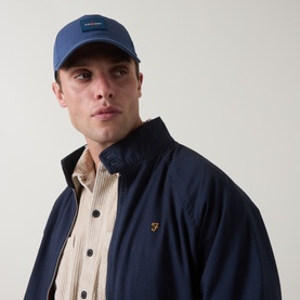 Model with Calvin Klein Monogram Logo Cap in Dark Denim, curved visor, worn with navy jacket and striped shirt.