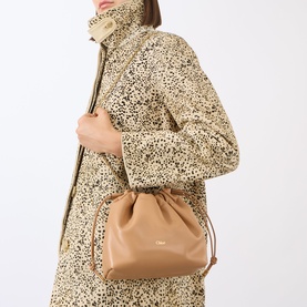 Model carrying Chlo&eacute; Icons Leather Mini Crossbody Bag in Light Tan, gold-tone hardware, drawstring top, styled with leopard-print coat