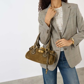Model carrying Chloe Paddington Suede Shoulder Bag in deep khaki with gold-toned hardware and padlock charm, styled with grey blazer and jeans