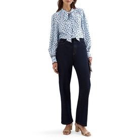 Model wearing Phase Eight blue polka dot tie-neck blouse with dark navy bootcut jeans and nude mule heels.