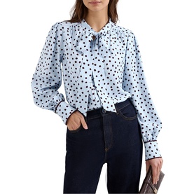 Model wearing Phase Eight blue polka dot bow-neck blouse with long bishop sleeves, styled with dark navy jeans