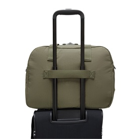Kipling Almost Sage green duffle bag with luggage sleeve, shown threaded onto black trolley suitcase handle from rear view.