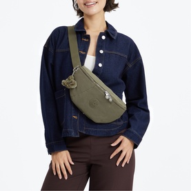 Model carrying a green Kipling crossbody bum bag with adjustable strap and signature monkey keychain, styled with denim jacket
