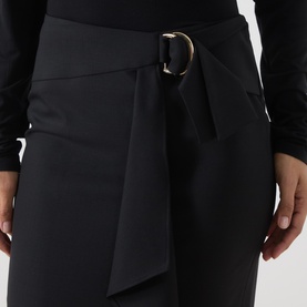 Model wearing Max Mara Studio nero wool skirt with wrap-style front panel and gold D-ring belt detail, paired with black top.