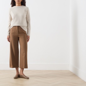 Model wearing Max Mara Studio Tobacco wool wide-leg cropped trousers, styled with a cream knit jumper and flat mules.
