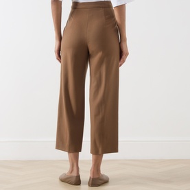 Model wearing Max Mara Studio Tobacco wide-leg cropped wool trousers, back view, styled with white top and beige sandals.
