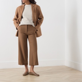 Model wearing Max Mara Studio Tobacco wool wide-leg trousers, styled with matching blazer, cream top and tan flat mules.
