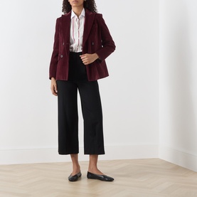 Model wearing Max Mara Studio black wide-leg cropped wool trousers, styled with a burgundy blazer, white shirt and black ballet flats.