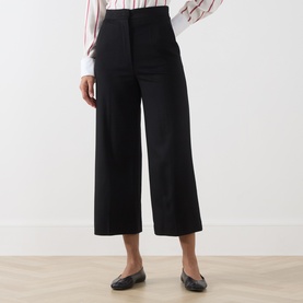 Model wearing Max Mara Studio black wide-leg cropped wool trousers, styled with a striped shirt and black flat loafers