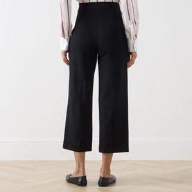 Model wearing Max Mara Studio black wide-leg wool trousers, rear view, styled with a striped blouse and black flat shoes.