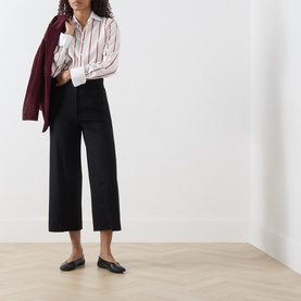 Model wearing Max Mara Studio black wool wide-leg cropped trousers, styled with a striped shirt, burgundy blazer, and black loafers.
