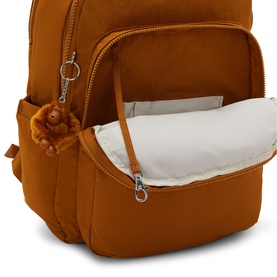 Kipling rust orange backpack with open front pocket revealing padded interior, silver-tone zips and signature monkey keyring charm