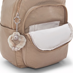 Kipling beige backpack with open front zip pocket, padded interior, and signature monkey keyring charm