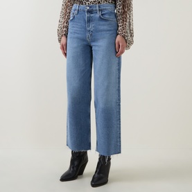 Model wearing AgoldE Wide Leg jeans in Measure blue denim with raw hem, styled with black ankle boots and leopard print top.