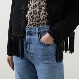 Model wearing AgoldE Measure wide leg jeans in light blue denim, styled with a black fringed jacket and leopard print top.